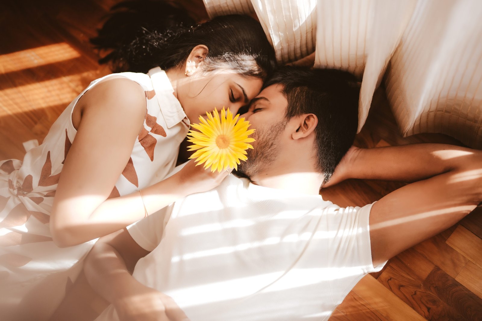 Couple sharing an intimate moment holding a yellow flower, captured by The Magic Hues
